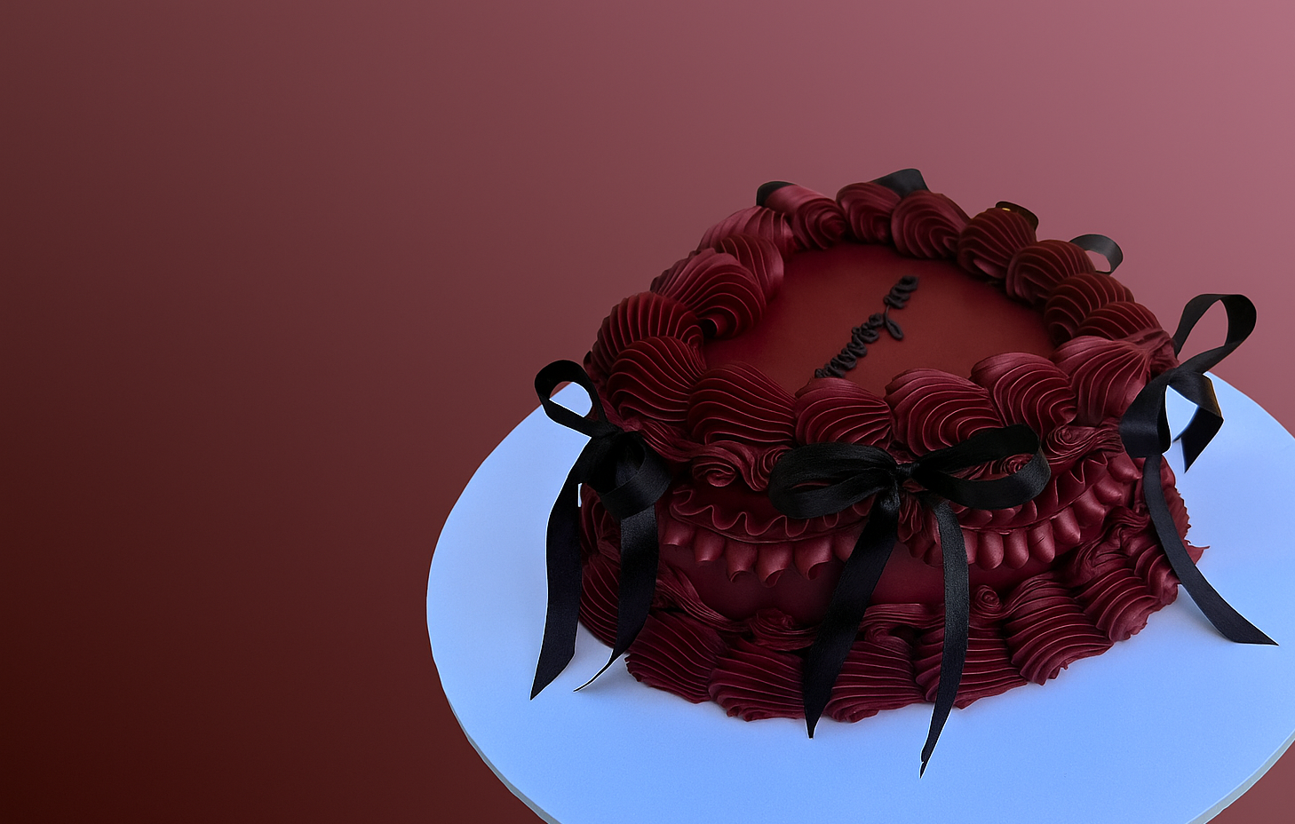 Red cake with black ribbons on a white plate against a red background